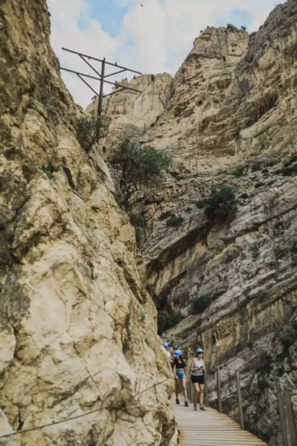 Hikers walking the cliffside boardwalks of Caminito del Rey gorge on a guided visit